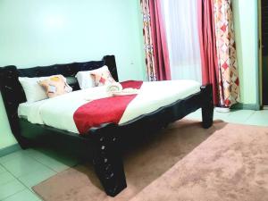 a black bed with a red and white comforter at SwanLakeview3br, Wi-Fi, Netflix, Balcony, Sunset. in Kisumu