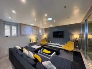 a living room with a black couch and yellow chairs at Appartement Standing piscine intérieur privatisée . in Mutzig