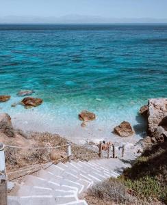a staircase leading to a beach with blue water at Cavo piso livadi in Piso Livadi