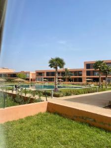 um resort com piscina, palmeiras e um edifício em Appartement luxe avec piscine Marrakech em Marrakech