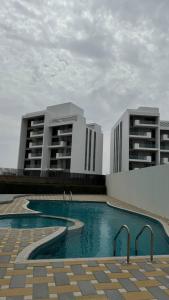 two buildings with a swimming pool in front of two buildings at شقة فندقية ALzorah Ajman - الزوراء عجمان in Ajman 