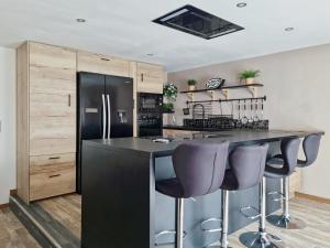 a kitchen with a black refrigerator and purple bar stools at les piafs du der 1 in Joncreuil