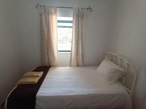 a bed in a room with a window at Casa dos avós in São Brás de Alportel