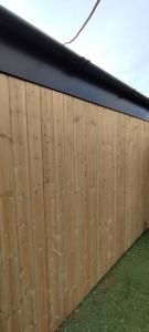 a wooden fence with a black top and green grass at The Nook: Self Contained Annex in Taunton