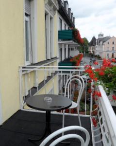 uma mesa e duas cadeiras numa varanda com flores em Gästehaus Vis-A-Vis em Rüdesheim am Rhein