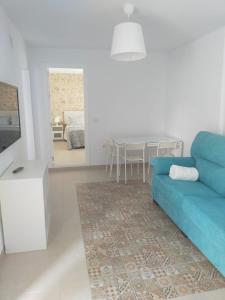 sala de estar con sofá azul y comedor en Casa Correos en Medina Sidonia
