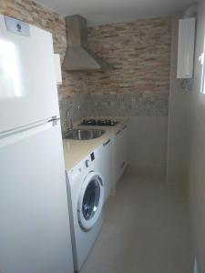 a kitchen with a white refrigerator and a washing machine at Casa Correos in Medina Sidonia