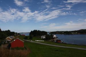 una casa roja en una colina junto a un cuerpo de agua en Åkviktunet hytte Sør, en Averoy