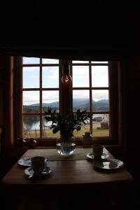 una mesa con dos tazas y un jarrón con una planta en una ventana en Åkviktunet hytte Sør, en Averoy