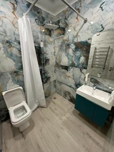 a bathroom with a toilet and a sink at Lux Plaza Hotel in Arbatʼ