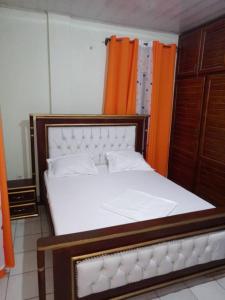 a bedroom with a large white bed with an orange curtain at RESIDENCE WALNICK in Douala