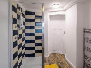 a bathroom with a shower with blue and white tiles at Forest side cottage in Nottingham