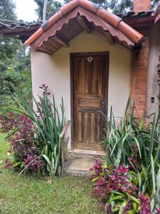 une petite maison avec une porte en bois et quelques plantes dans l'établissement Pousada Céu Aberto - Visconde de Mauá - Maringá MG, à Itatiaia