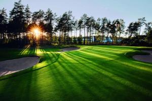 a golf course with the sun shining on the greens at House by the ocean in Halmstad