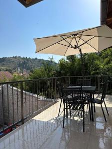 a table and chairs with an umbrella on a balcony at Cuprija _apartments in Stolac