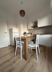 cocina con mesa de madera y sillas blancas en Casa di Maya, en Portacomaro