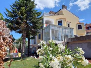 una casa con ventanas de cristal y un árbol en Apartman Amfora, en Malinska