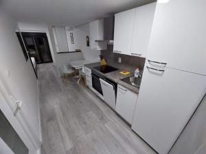 uma cozinha com armários brancos e piso em madeira em Apartman Amfora em Malinska