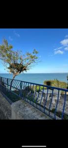 a blue railing next to the ocean with a tree at Appartement vue sur mer in Plérin