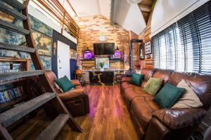 a living room with a leather couch and a television at City Style Lofts in Sheffield