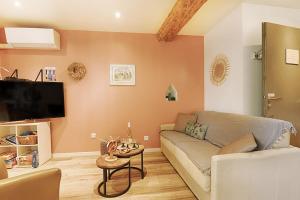 ein Wohnzimmer mit einem Sofa und einem TV in der Unterkunft BREDALA**** Gîte maison Alsacienne avec Jardin in Eguisheim