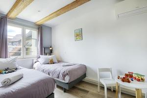 1 Schlafzimmer mit 2 Betten, einem Tisch und einem Fenster in der Unterkunft BREDALA**** Gîte maison Alsacienne avec Jardin in Eguisheim