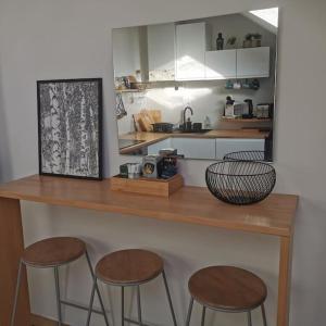 una cocina con 3 taburetes y una encimera con encimera en Expérience Cocooning typé Loft en Braux