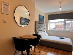 a bedroom with a bed and a table and a mirror at High-End Central Luton Studio - Ideal for Airport! in Luton