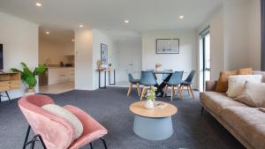 ein Wohnzimmer mit einem Sofa, Stühlen und einem Tisch in der Unterkunft Stylish 4 Bedroom house Brand New in Rotorua in Rotorua