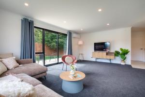 a living room with a couch and a tv at Stylish 4 Bedroom house Brand New in Rotorua in Rotorua