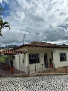 a white house with a palm tree in front of it at Pertin da Praça Hostel in Ouro Preto