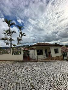 una casa blanca con palmeras delante en Pertin da Praça Hostel, en Ouro Preto