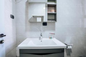 a white bathroom with a sink and a mirror at Amnen Apartments in Addis Ababa