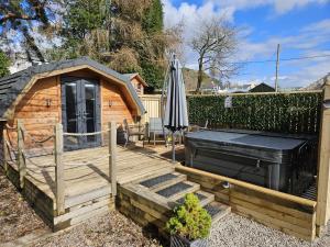 eine Holzterrasse mit einem Sonnenschirm und einem Haus in der Unterkunft Morvan Pod & Hot tub in Fort William