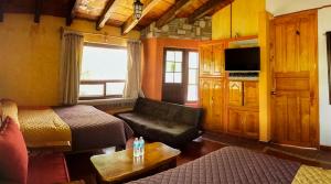 a room with two beds and a couch and a tv at Hotel Villas San Miguel in Pátzcuaro