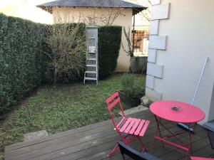 a red chair and a table on a deck at STUDIO MEUBLÉ JO PROCHE VÉLODROME in Voisins-le-Bretonneux