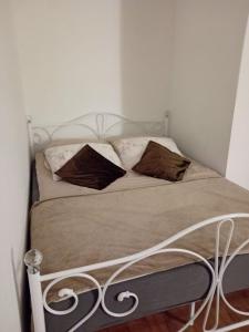 Una cama con marco de metal y almohadas. en Amelia1, en Toruń