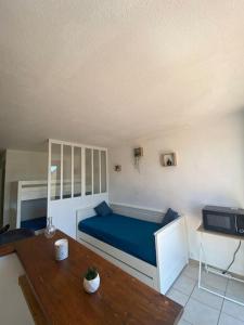 Schlafzimmer mit einem blauen Bett und einem Holztisch in der Unterkunft Appart 5 min à pied de la plage in Cap d'Agde