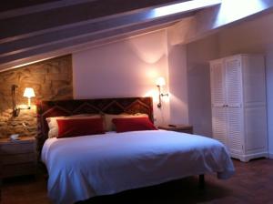 a bedroom with a large white bed with red pillows at Hotel El Cerco in Puente la Reina