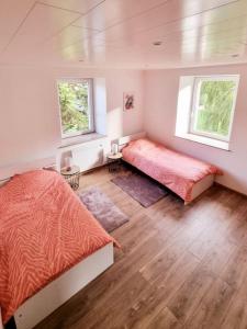 1 dormitorio con 2 camas y 2 ventanas en Appartement chaleureux 80m2, en Orbey