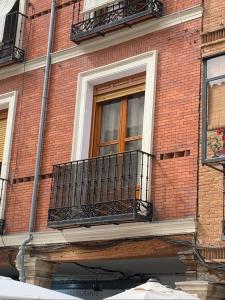 a window on a brick building with a balcony at Calle Mayor in Alcalá de Henares