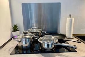 three pots and pans sitting on top of a stove at Living at Saarpartments - AdultsOnly - Business & Holiday Homes with Kitchen for Long- and Short Term stay, 3 min to St Johanner Markt and Points of Interest in Saarbrücken