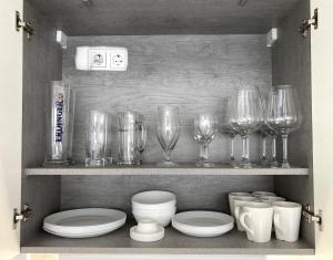 a shelf with wine glasses and plates and bowls at Living at Saarpartments - AdultsOnly - Business & Holiday Homes with Kitchen for Long- and Short Term stay, 3 min to St Johanner Markt and Points of Interest in Saarbrücken