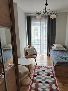 a bedroom with two beds and a chair and a mirror at Apartament na Tatarskiej z widokiem in Przemyśl