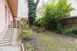 a garden with two benches and a fence at Central Serenity: Urban Garden Retreat in Bratislava