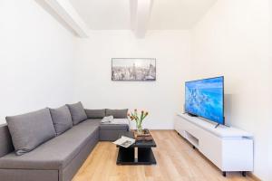 a living room with a gray couch and a flat screen tv at Central Serenity: Urban Garden Retreat in Bratislava