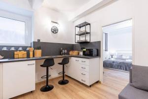 a kitchen with white cabinets and black stools at Central Serenity: Urban Garden Retreat in Bratislava