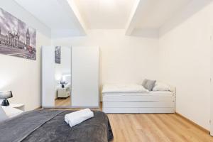a white bedroom with a bed and a mirror at Central Serenity: Urban Garden Retreat in Bratislava