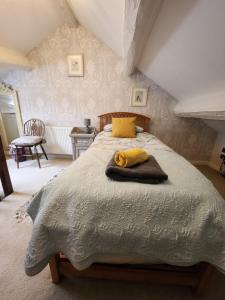 a bedroom with a bed with a yellow towel on it at East Cote Cottage in Settle