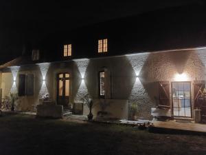 une maison avec des lumières sur son côté la nuit dans l'établissement L'Orangerie, à Idron
